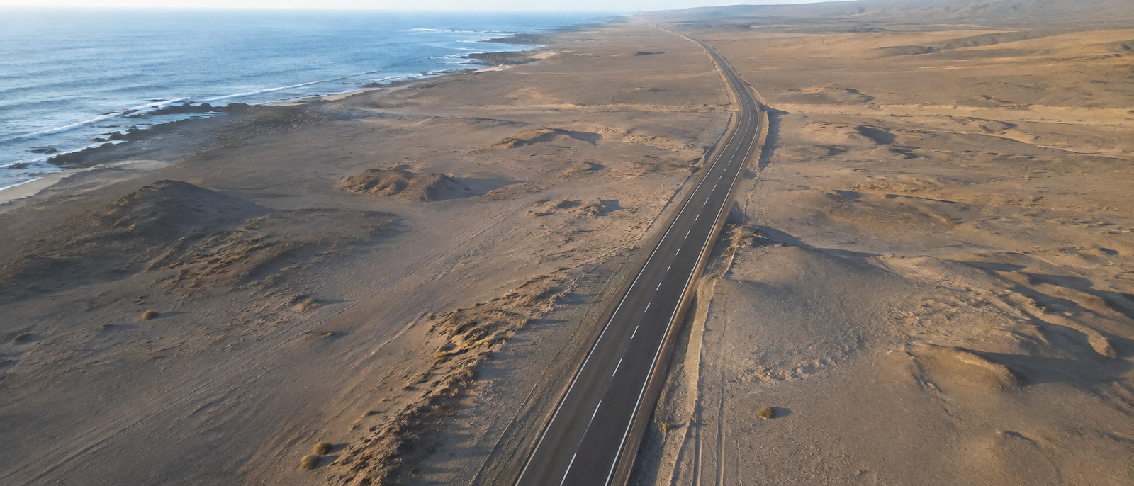 Vista aérea de una carretera junto a la costa, entre el mar y el desierto.